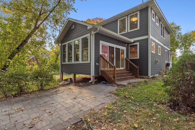 rear view of property featuring a sunroom and a patio area