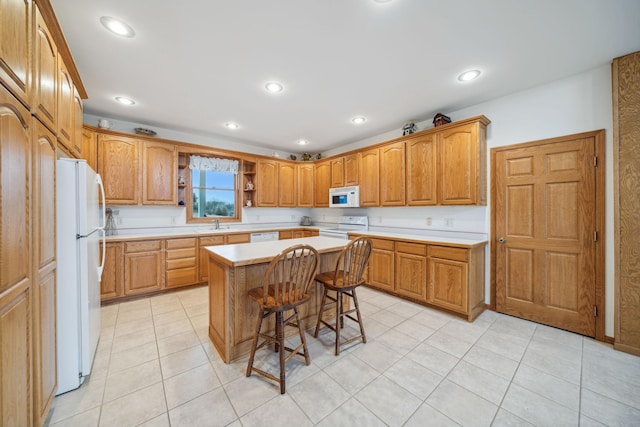 kitchen featuring a breakfast bar area, light tile patterned flooring, white appliances, and a center island