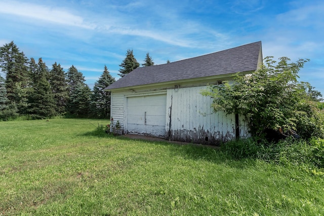 exterior space with a garage, an outbuilding, and a lawn