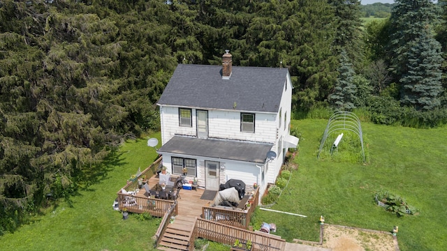 back of property featuring a wooden deck and a lawn