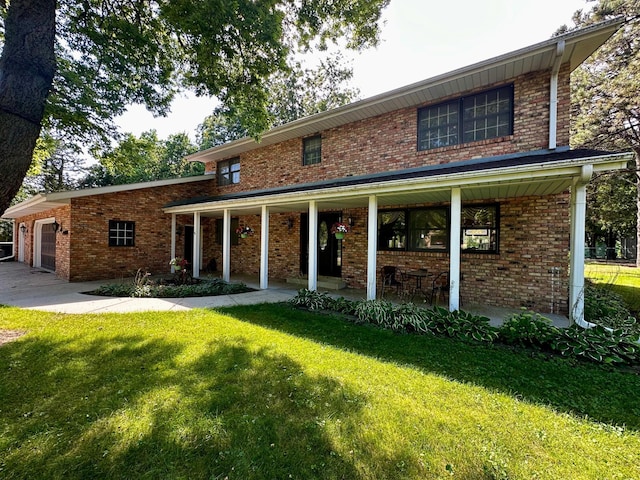 back of house with a garage, covered porch, a lawn, and brick siding