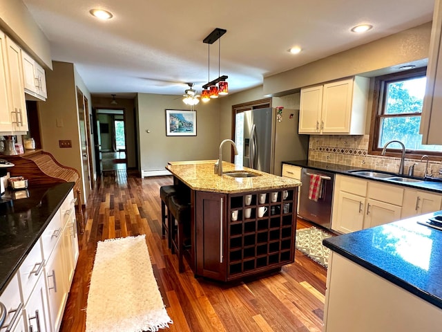 kitchen featuring a center island with sink, pendant lighting, stainless steel appliances, and a sink