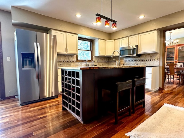 kitchen with appliances with stainless steel finishes, a kitchen island, white cabinetry, and tasteful backsplash