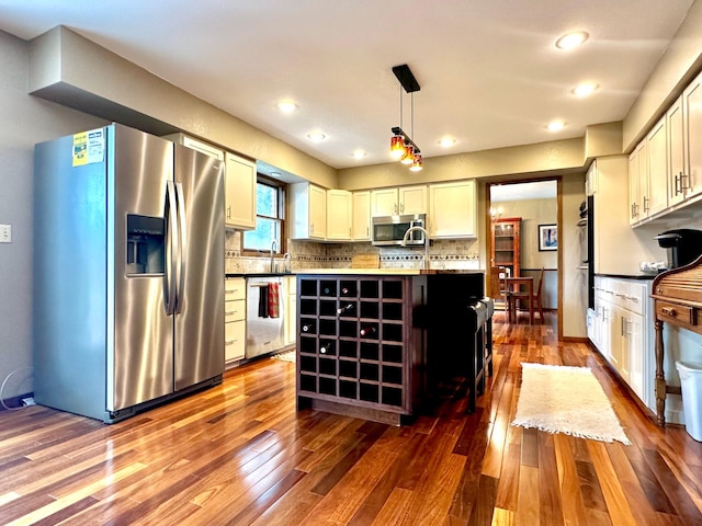 kitchen with hanging light fixtures, appliances with stainless steel finishes, a kitchen island with sink, and white cabinetry