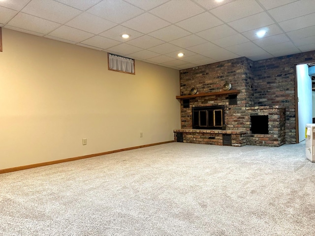 unfurnished living room with carpet floors, a brick fireplace, baseboards, and a paneled ceiling