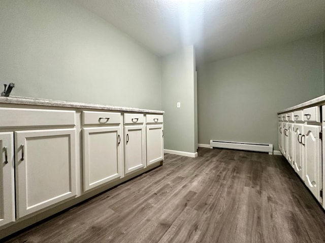 laundry area featuring a baseboard heating unit, baseboards, and dark wood-style floors