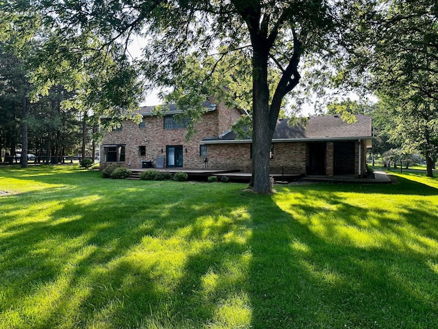 back of house featuring brick siding and a yard