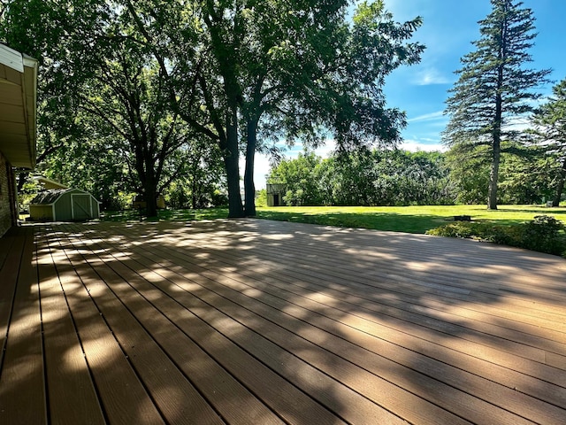 wooden terrace featuring an outbuilding, a storage unit, and a lawn