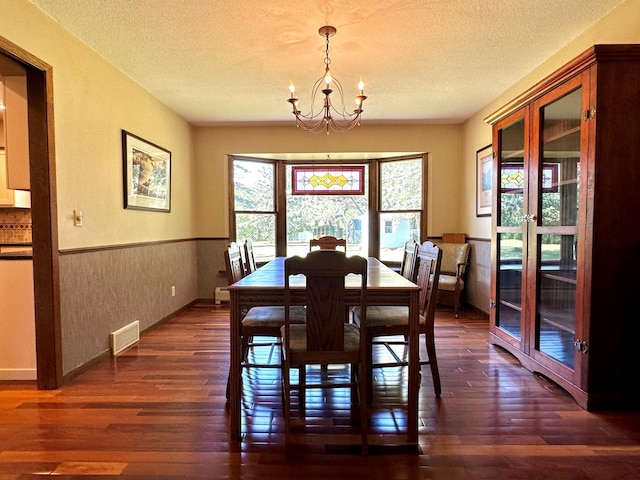 dining area featuring a wainscoted wall, a textured ceiling, dark wood-style floors, and visible vents