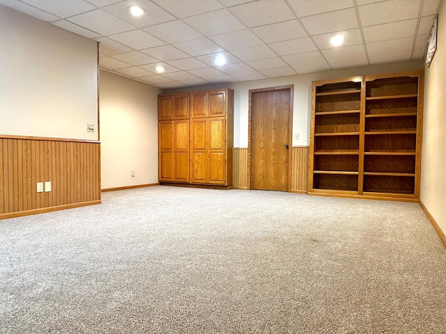 unfurnished room featuring light colored carpet, wainscoting, and wood walls