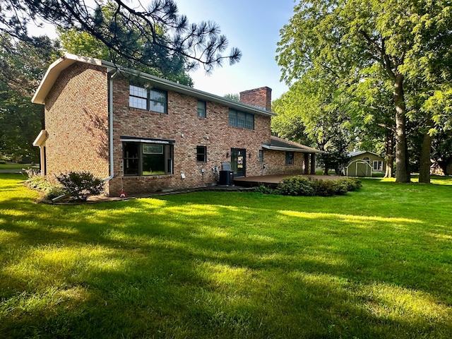 rear view of property featuring an outbuilding, brick siding, a yard, a chimney, and a shed