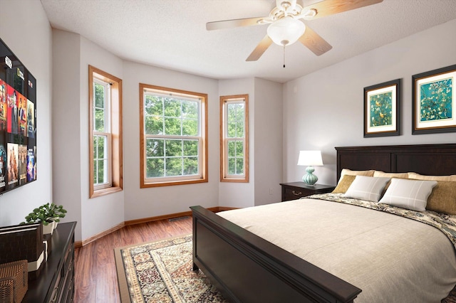 bedroom with ceiling fan, dark hardwood / wood-style flooring, and a textured ceiling