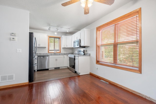 kitchen with stainless steel appliances, white cabinetry, sink, and dark wood-type flooring