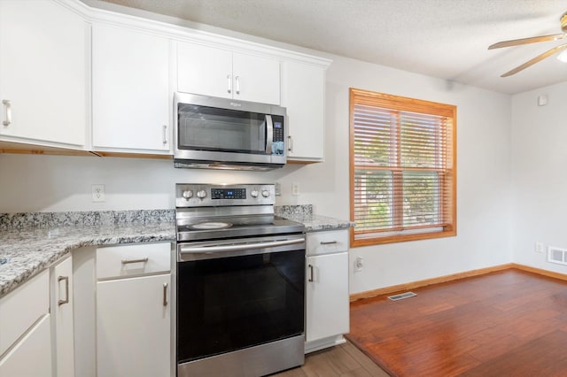 kitchen featuring white cabinetry, ceiling fan, stainless steel appliances, light stone countertops, and light hardwood / wood-style flooring