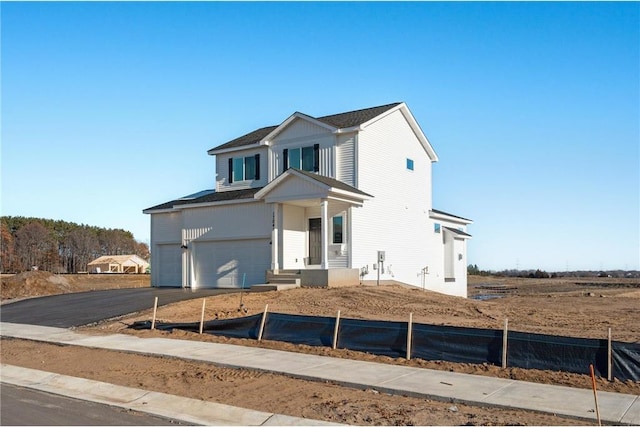 traditional home featuring an attached garage, fence, and aphalt driveway