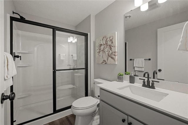 bathroom featuring toilet, wood finished floors, visible vents, vanity, and a shower stall