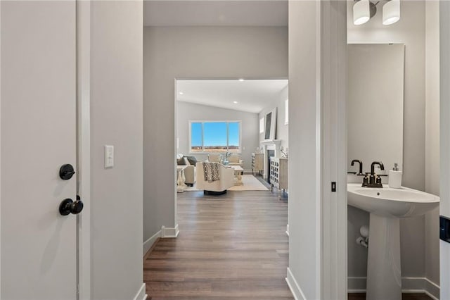 interior space with vaulted ceiling, a fireplace, wood finished floors, and baseboards