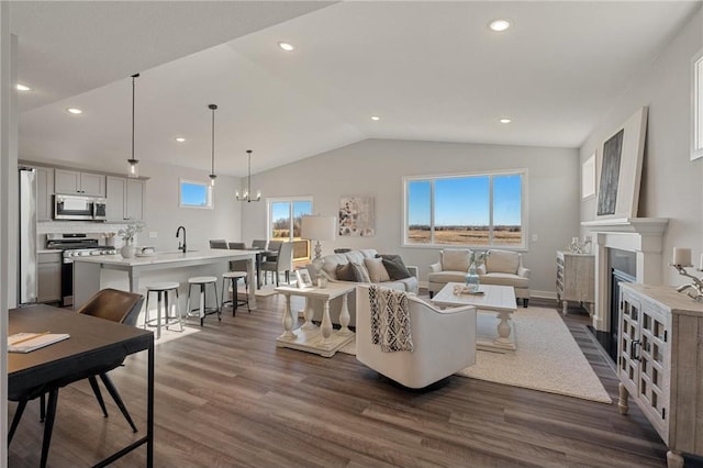 living area with lofted ceiling, recessed lighting, a notable chandelier, dark wood-type flooring, and a fireplace with flush hearth