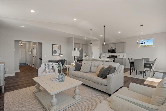 living area featuring an inviting chandelier, vaulted ceiling, wood finished floors, and recessed lighting