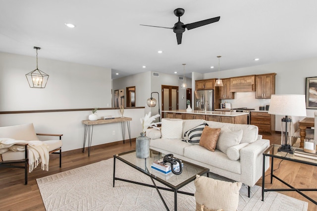 living room featuring ceiling fan with notable chandelier and light hardwood / wood-style flooring