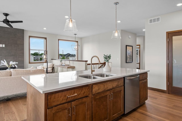 kitchen with dishwasher, a kitchen island with sink, hardwood / wood-style floors, pendant lighting, and sink