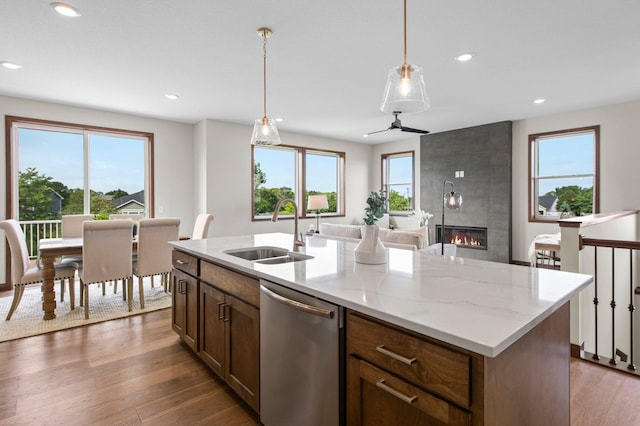 kitchen with stainless steel dishwasher, a fireplace, plenty of natural light, and a kitchen island with sink