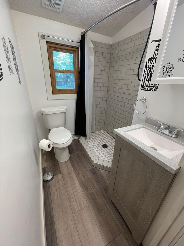 bathroom with toilet, hardwood / wood-style floors, a textured ceiling, and a shower with shower curtain