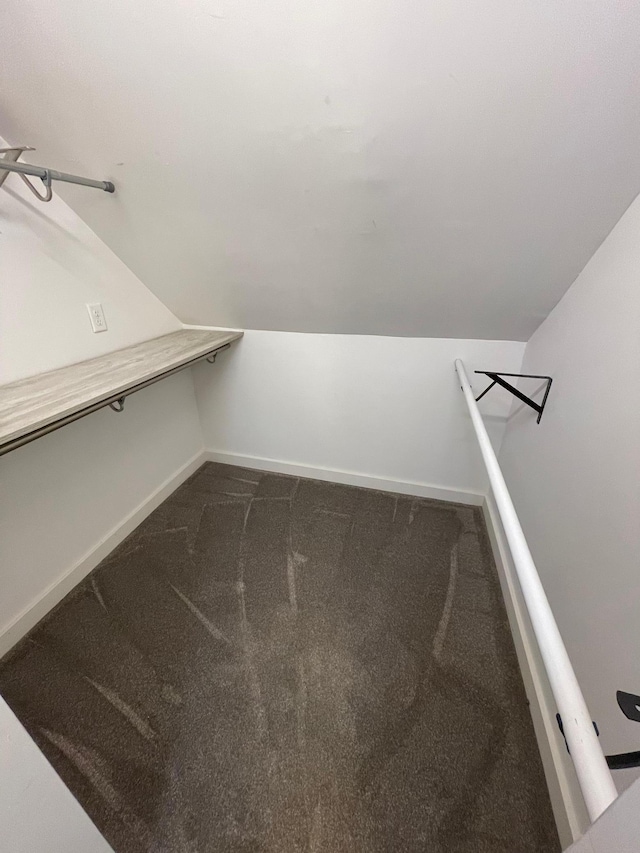 spacious closet featuring lofted ceiling and dark colored carpet