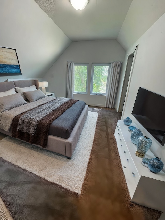 bedroom with vaulted ceiling and dark colored carpet