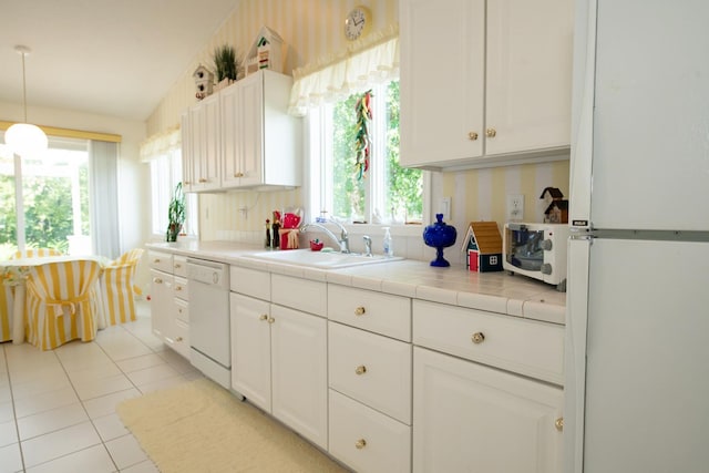 kitchen featuring tile countertops, white appliances, sink, and plenty of natural light