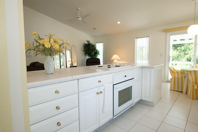 kitchen featuring white cabinetry, white appliances, light tile patterned floors, and tile countertops