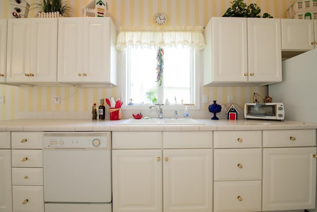 kitchen with sink, white dishwasher, and tile counters