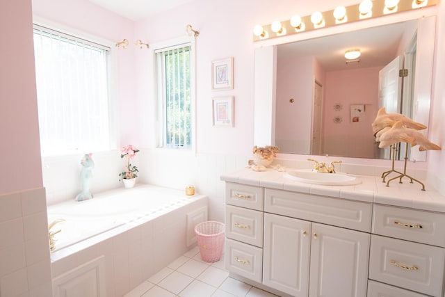 bathroom with tile patterned flooring, tiled tub, and vanity