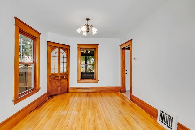 empty room featuring light hardwood / wood-style floors and an inviting chandelier