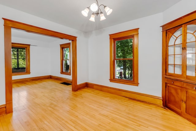 unfurnished room featuring light hardwood / wood-style flooring and a chandelier