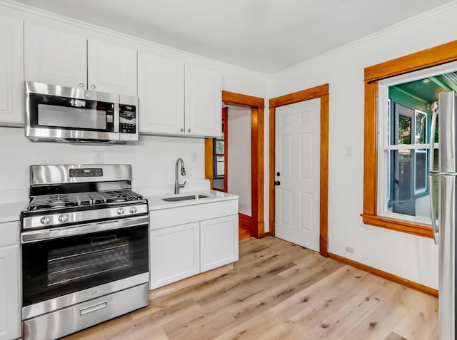 kitchen with white cabinets, appliances with stainless steel finishes, light wood-type flooring, and sink