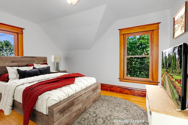 bedroom with hardwood / wood-style flooring, vaulted ceiling, and multiple windows