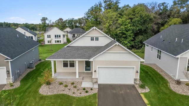 view of front of house featuring covered porch, cooling unit, a garage, and a front yard