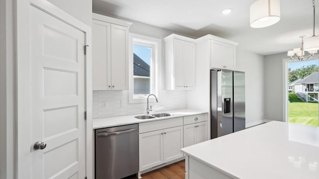 kitchen featuring white cabinets, stainless steel appliances, pendant lighting, sink, and tasteful backsplash