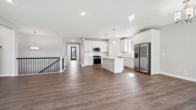 kitchen featuring white cabinets, stainless steel appliances, decorative light fixtures, and a center island