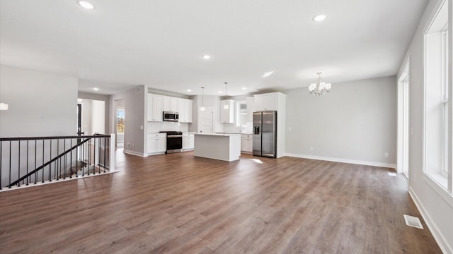 unfurnished living room featuring an inviting chandelier and wood-type flooring