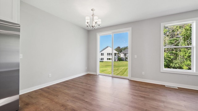 empty room featuring dark wood-type flooring and an inviting chandelier