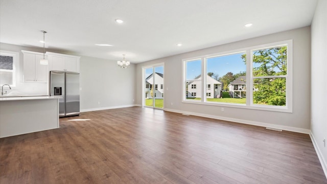 unfurnished living room with sink, dark hardwood / wood-style flooring, and a notable chandelier