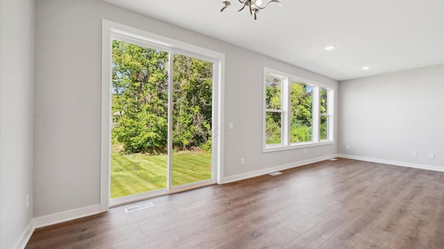 unfurnished room with a chandelier and wood-type flooring