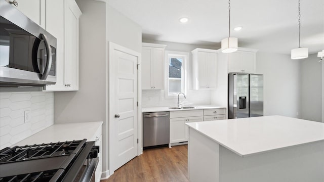 kitchen featuring sink, white cabinets, pendant lighting, and appliances with stainless steel finishes