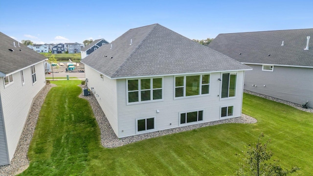 rear view of property featuring a lawn and central AC unit