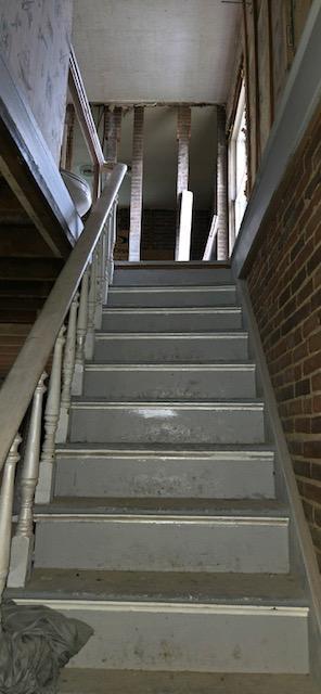 stairway featuring brick wall