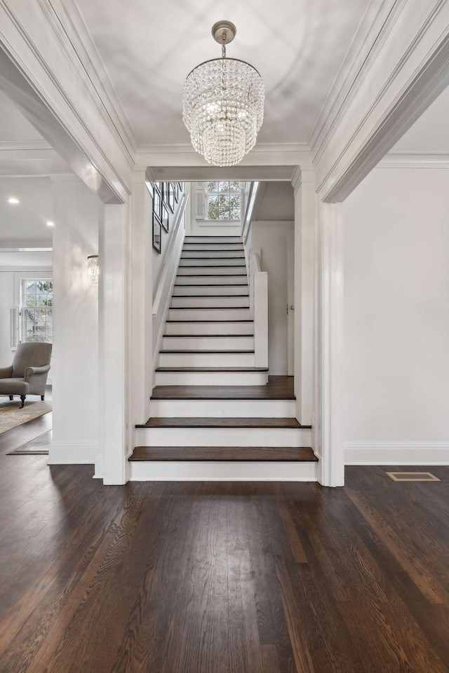 stairs featuring crown molding, wood-type flooring, and a chandelier