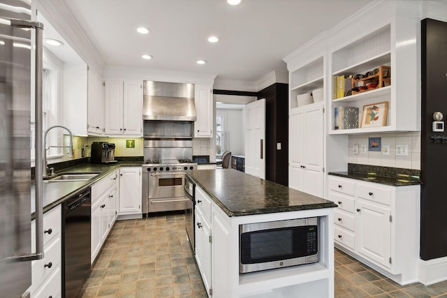 kitchen with a kitchen island, appliances with stainless steel finishes, wall chimney range hood, and white cabinets