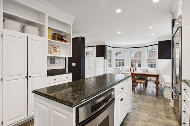 kitchen featuring white cabinetry, crown molding, stainless steel oven, and a kitchen island